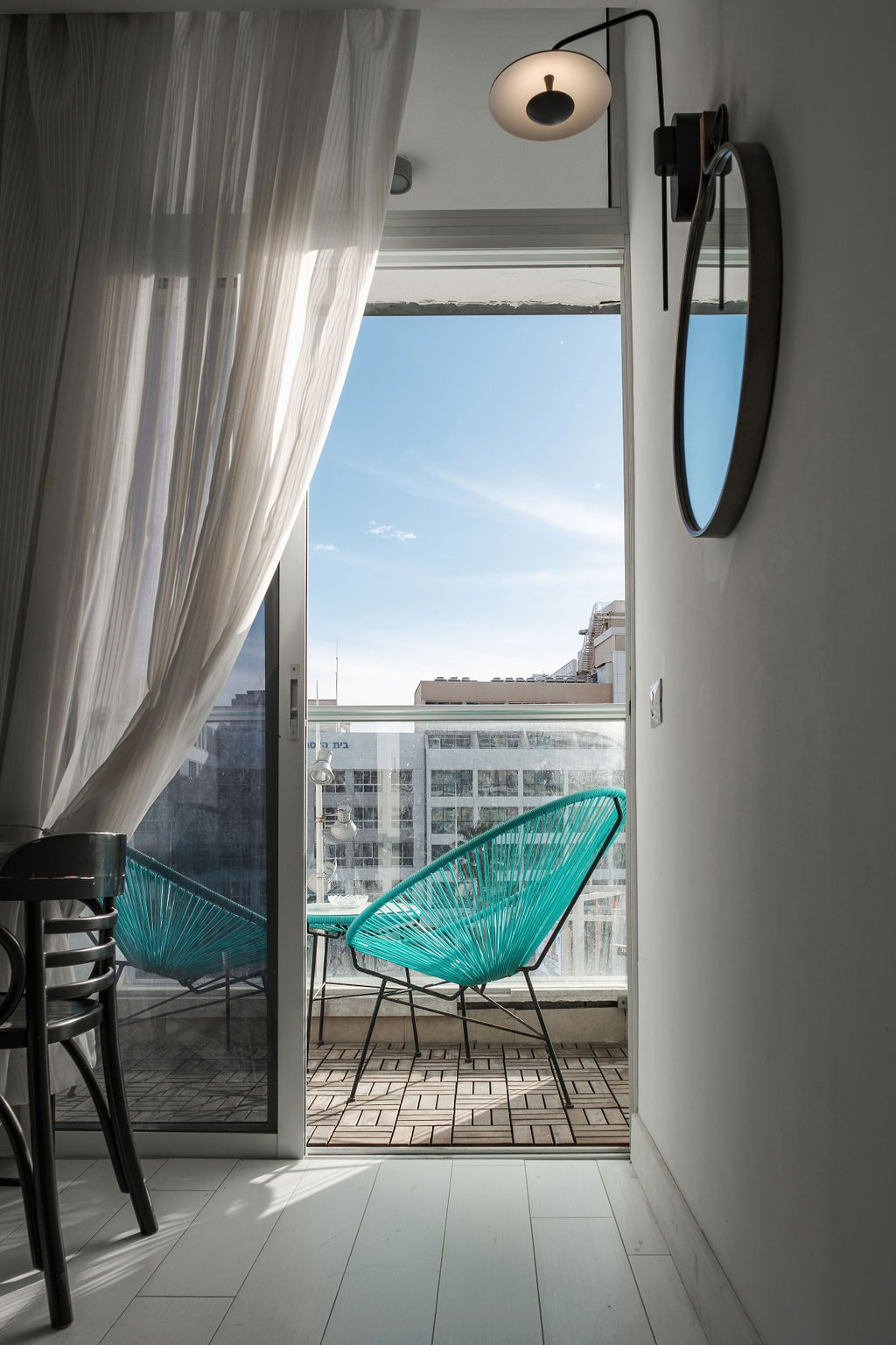 Vue depuis la chambre vers le balcon avec fauteuils Acapulco turquoise à l'Hotel Kikar Netanya